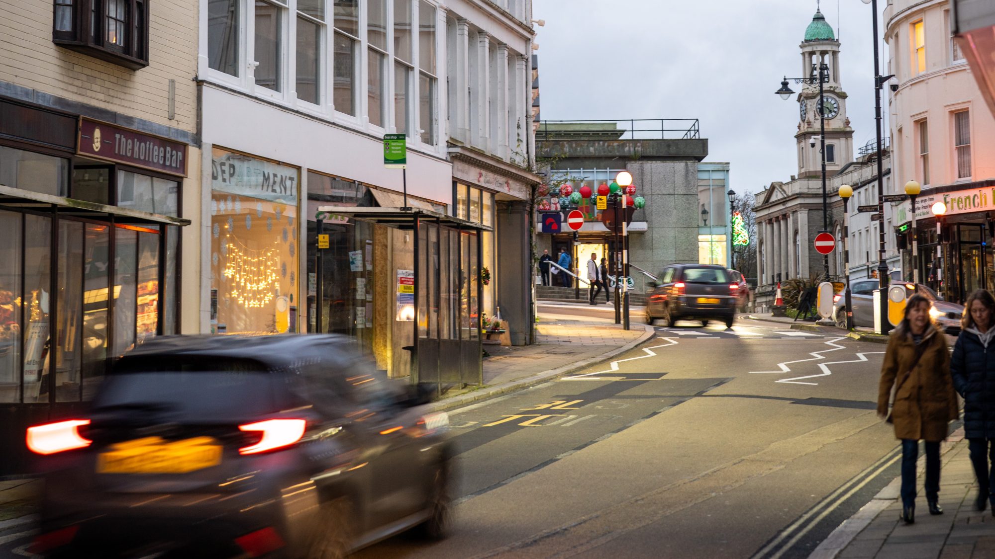 road of shops with a car driving along